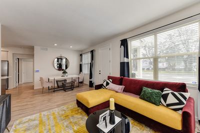 living room with red and yellow couch and Harwood inspired flooring. Dining area in the distance.